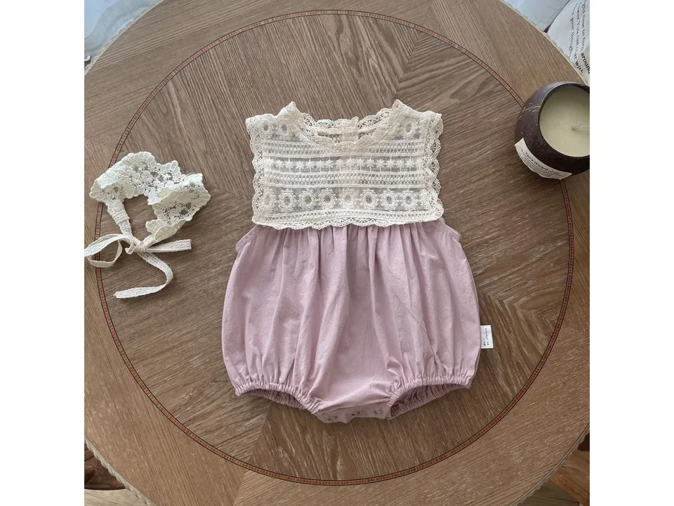 Pink baby romper and matching lace headband on a wooden table