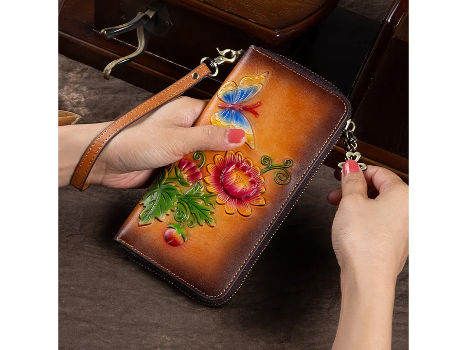 A person holding the long leather wallet with a wrist strap.