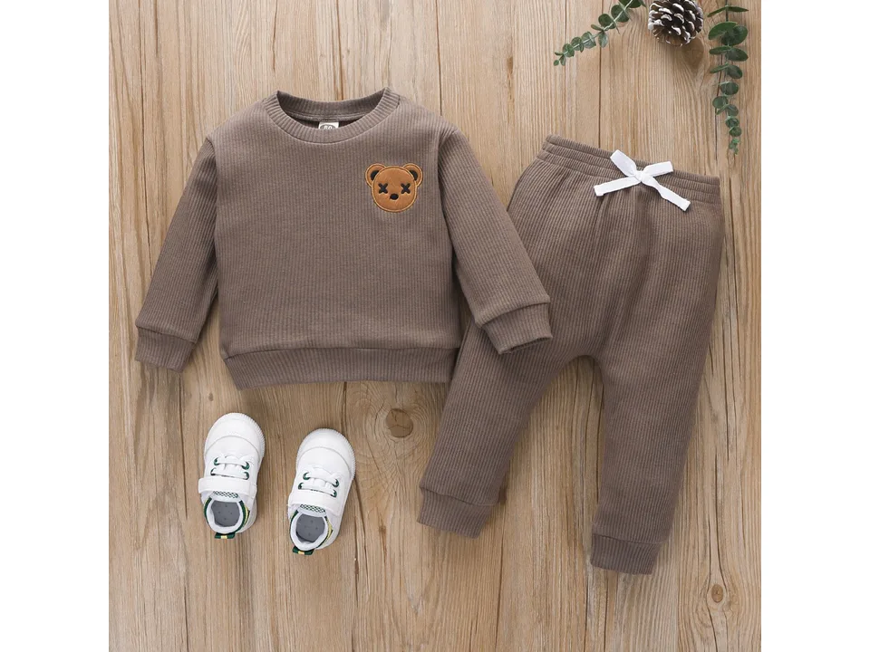 A brown children's bear embroidered long-sleeved top and trousers set laid out on a wooden surface.