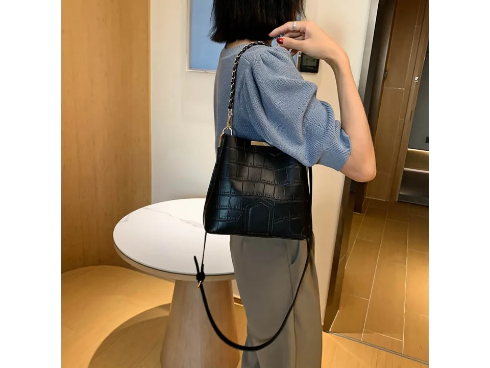 A person wearing the black bucket bag over their shoulder.