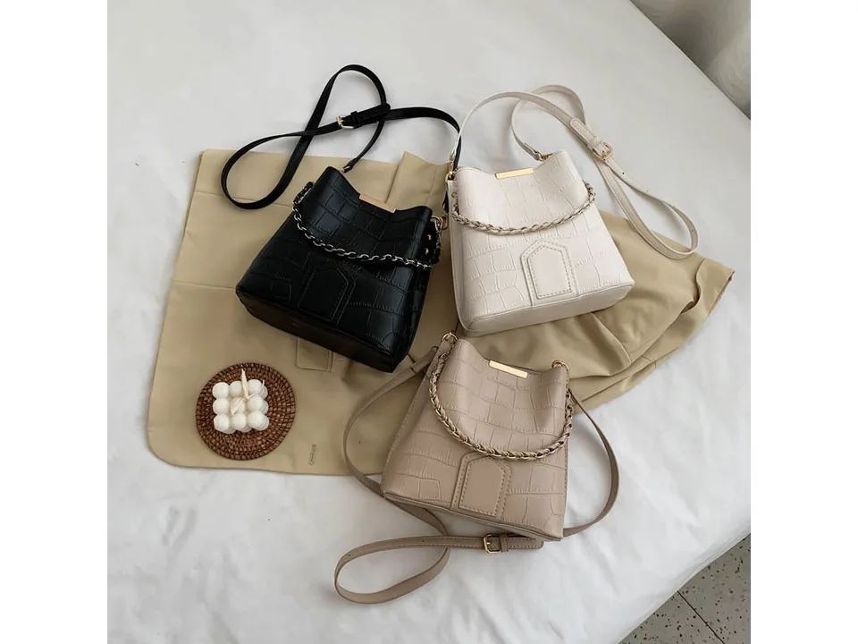 Three bucket bags in black, white, and beige displayed together.