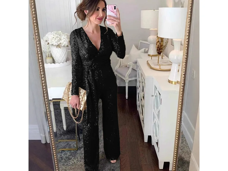 A woman wearing a black long-sleeve sequin jumpsuit with a waist tie.