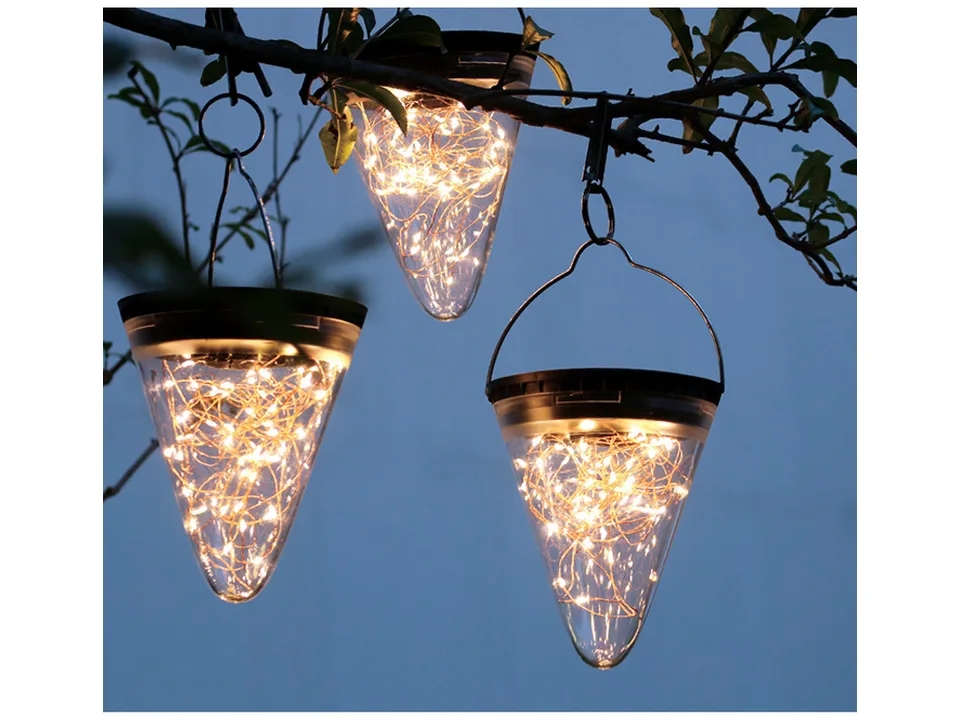 Three solar cone lights hanging from a tree branch at night.