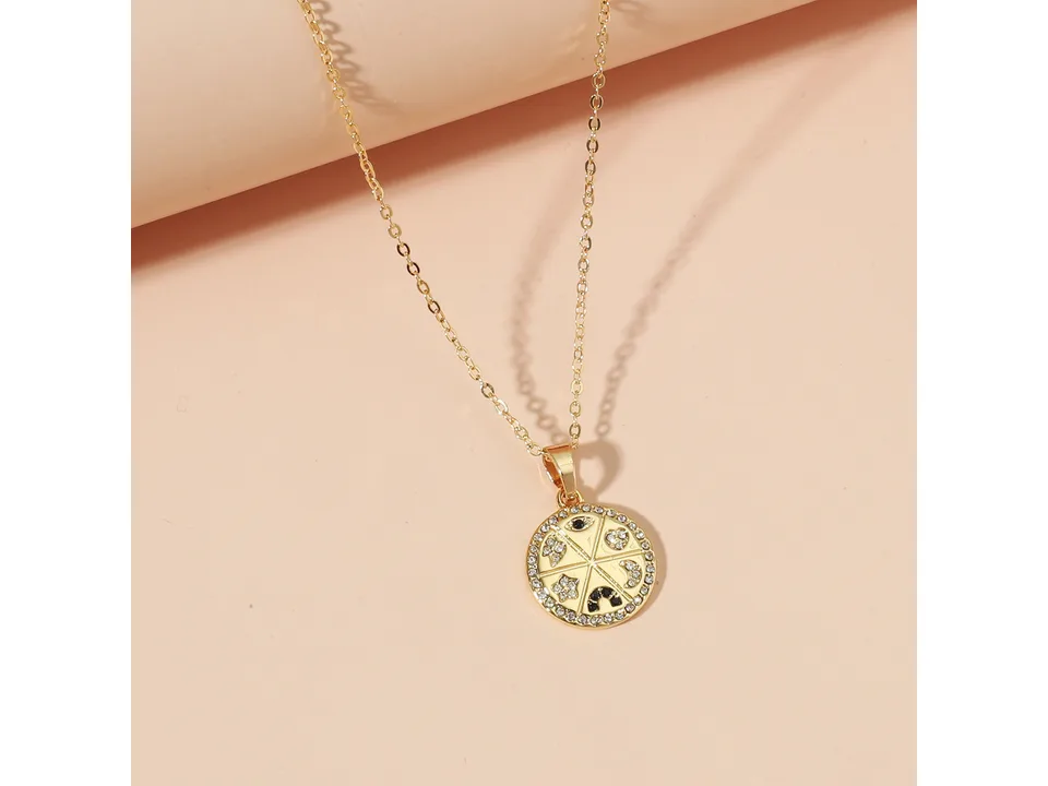 Close-up of a gold circular pendant necklace with rhinestone embellishments and celestial symbols.