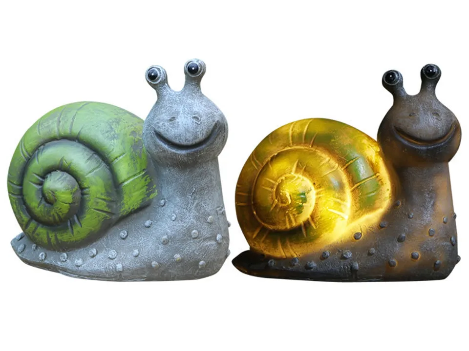 Two snail garden lamps, one unlit and one glowing with warm light.