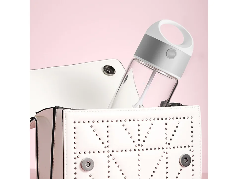 An electric stirring cup placed inside a white handbag.