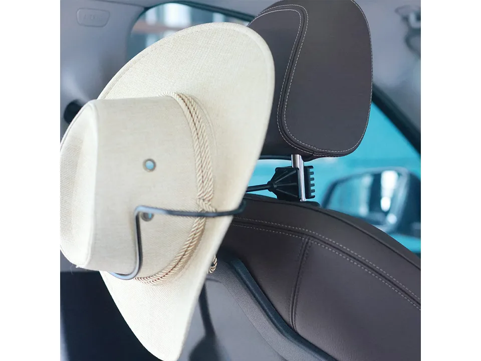 A cowboy hat hanging on the car headrest hanger.