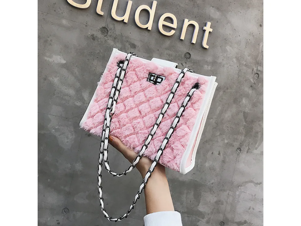 Hand holding a pink plush quilted handbag with chain strap