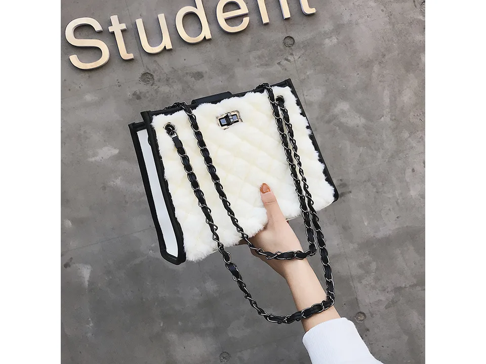 Hand holding a white plush quilted handbag with chain strap