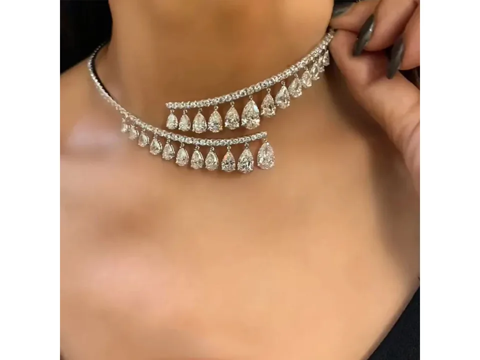 A person wearing a silver crystal drop choker necklace.