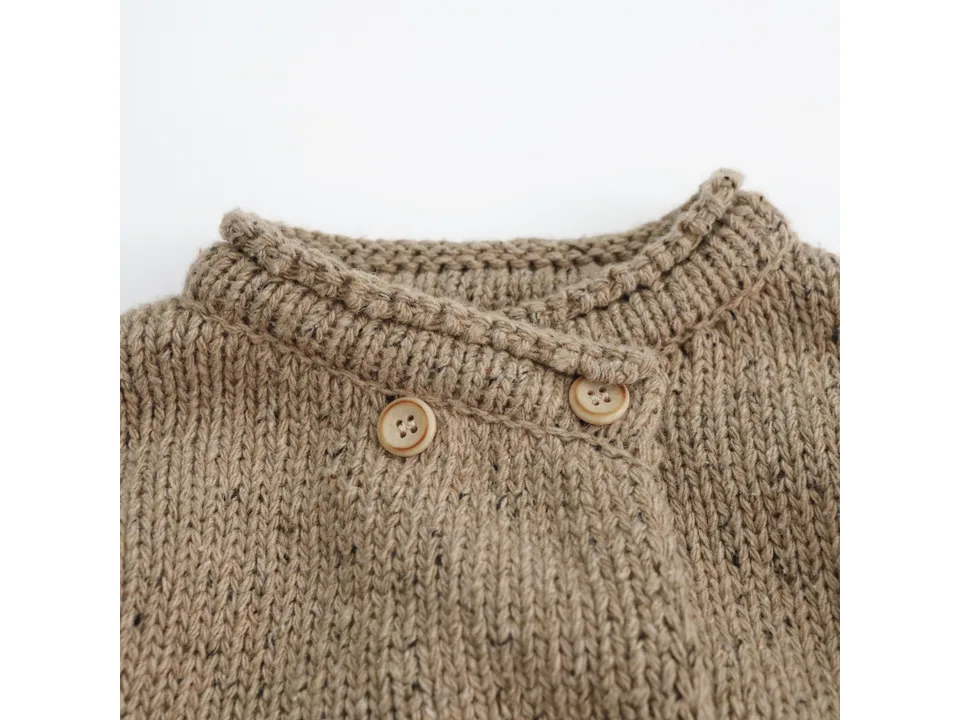 Close-up of the collar and button closure on the beige knitted cardigan.