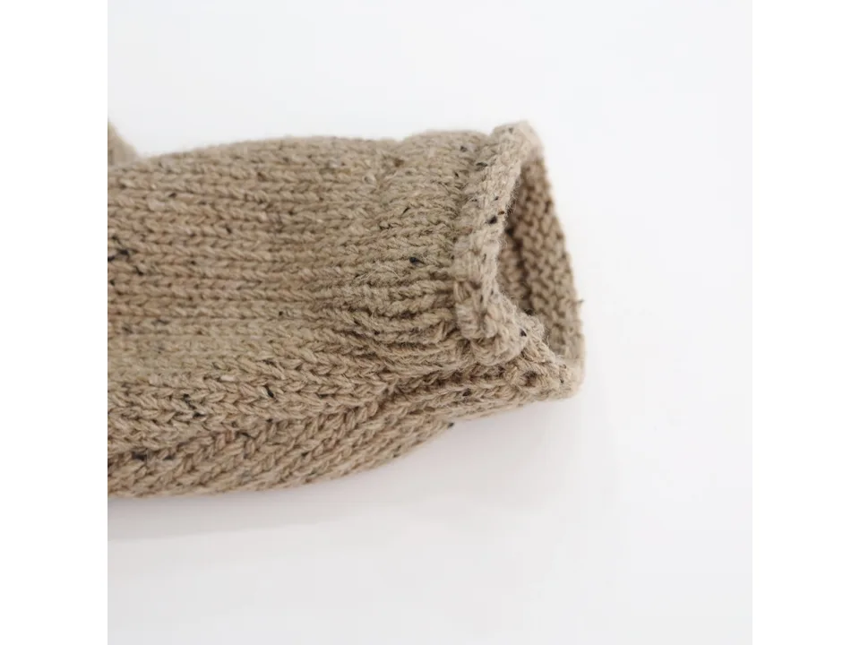 Close-up of the knitted sleeve cuff on the beige cardigan.