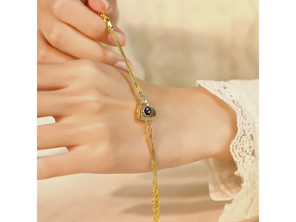 A gold double-layer heart projection bracelet worn on a woman's wrist.
