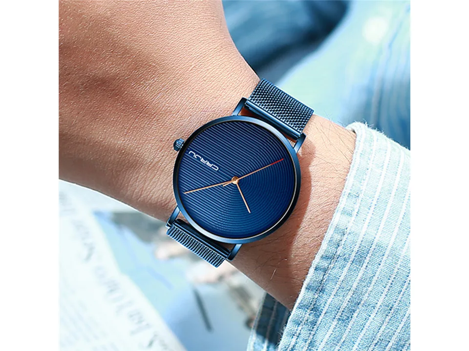 A blue CRRJU wristwatch with a mesh band worn on a man's wrist.