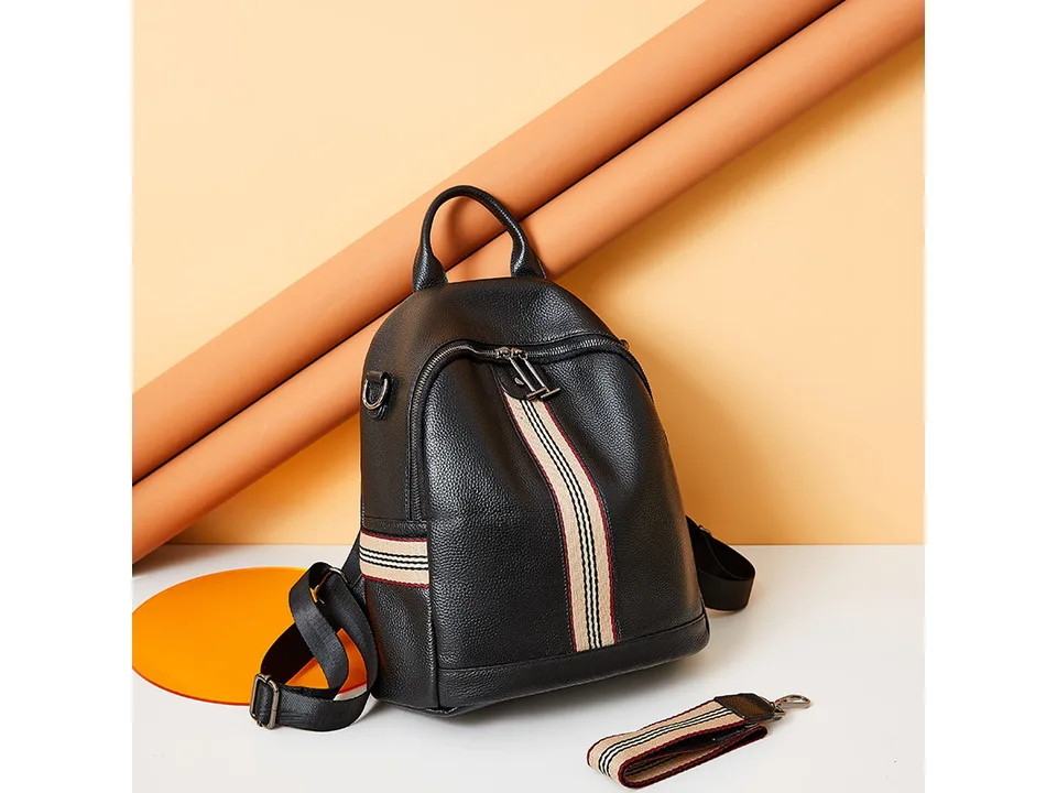 Black leather backpack displayed with a separate striped shoulder strap.