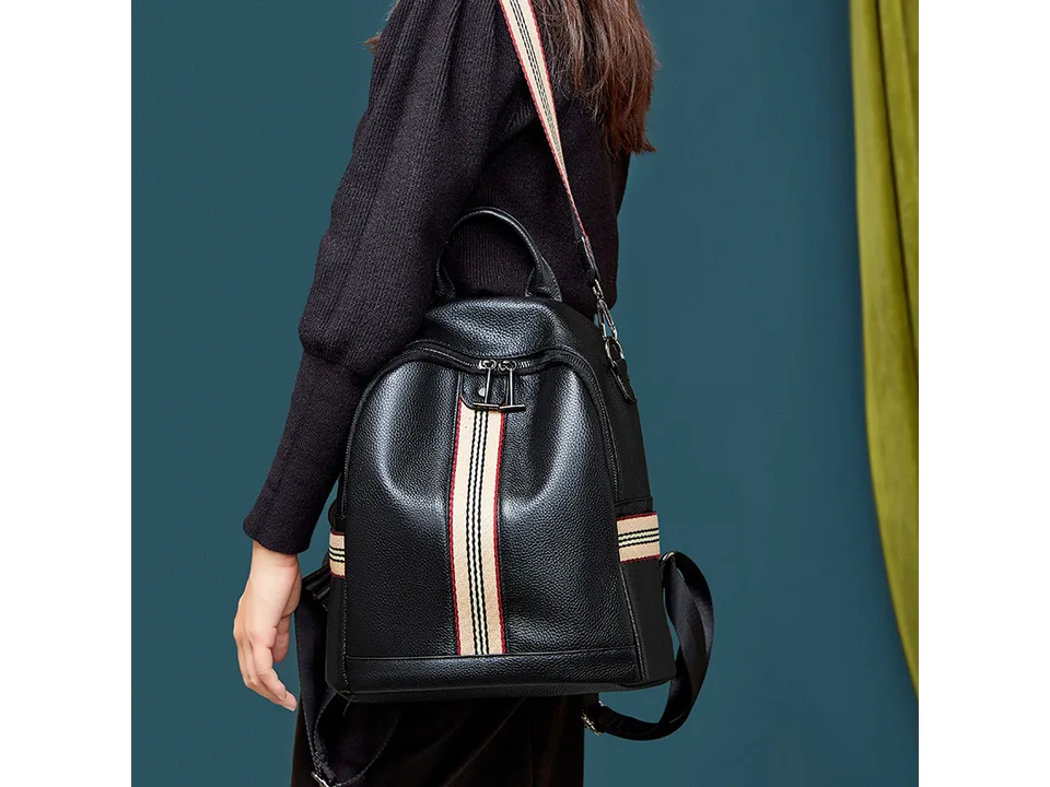 A woman wearing the black leather backpack with striped detailing.