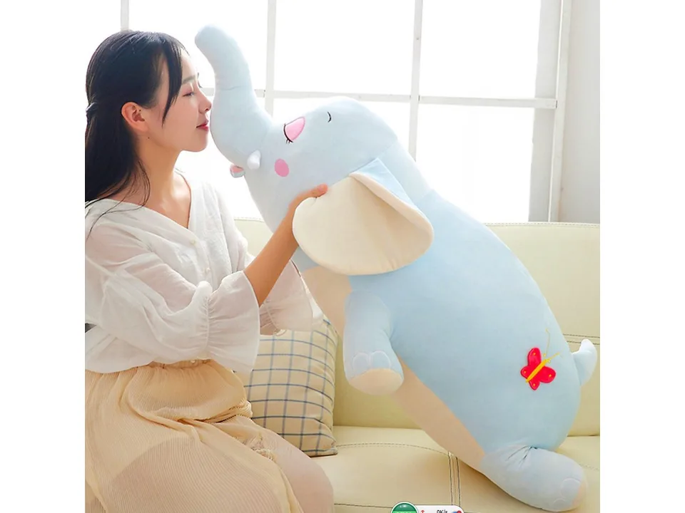 A woman holding a large blue elephant plush toy.