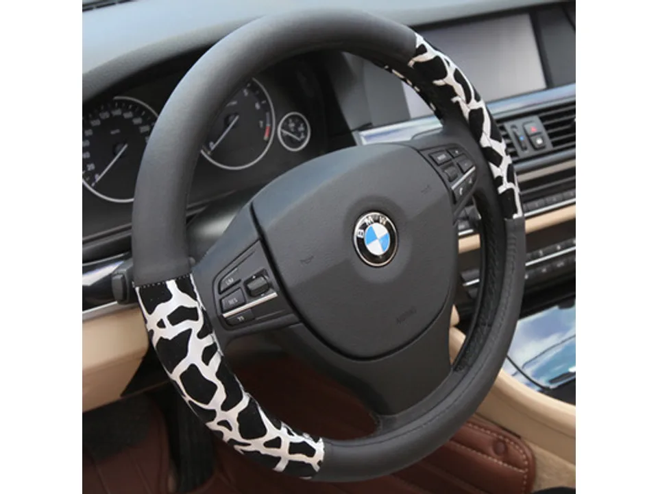 White and black animal print steering wheel cover installed on a car steering wheel.