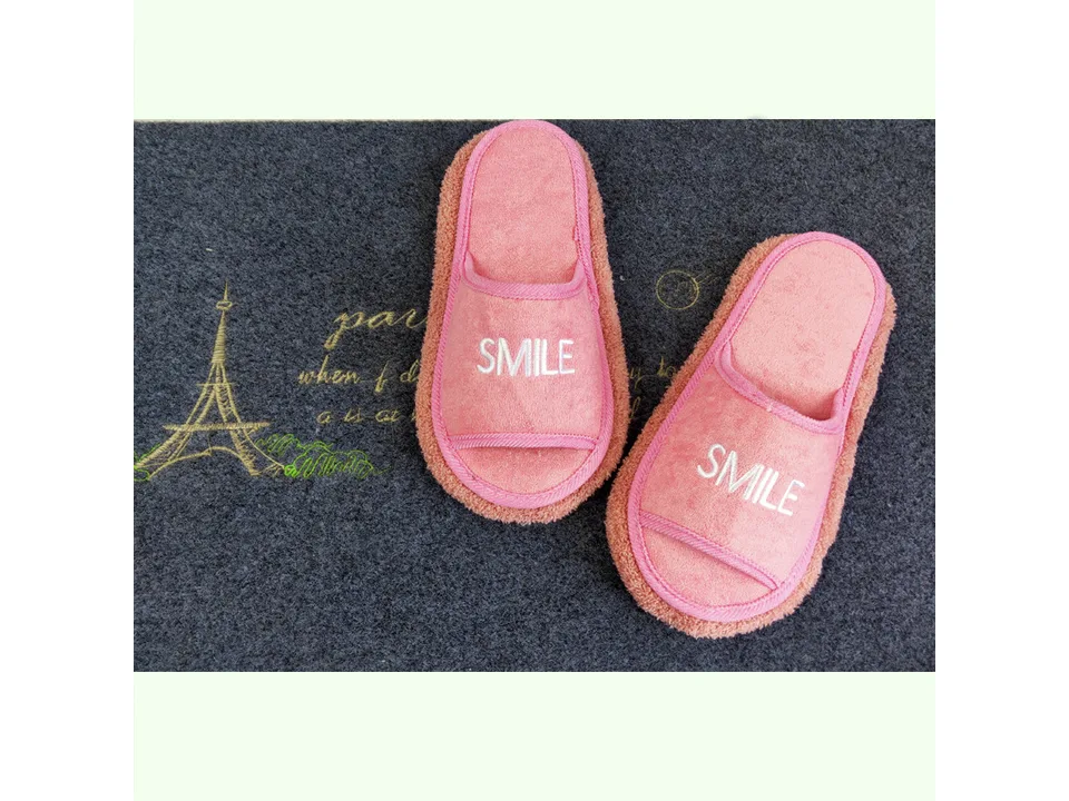A pair of pink open-toe slippers with the word SMILE on them.