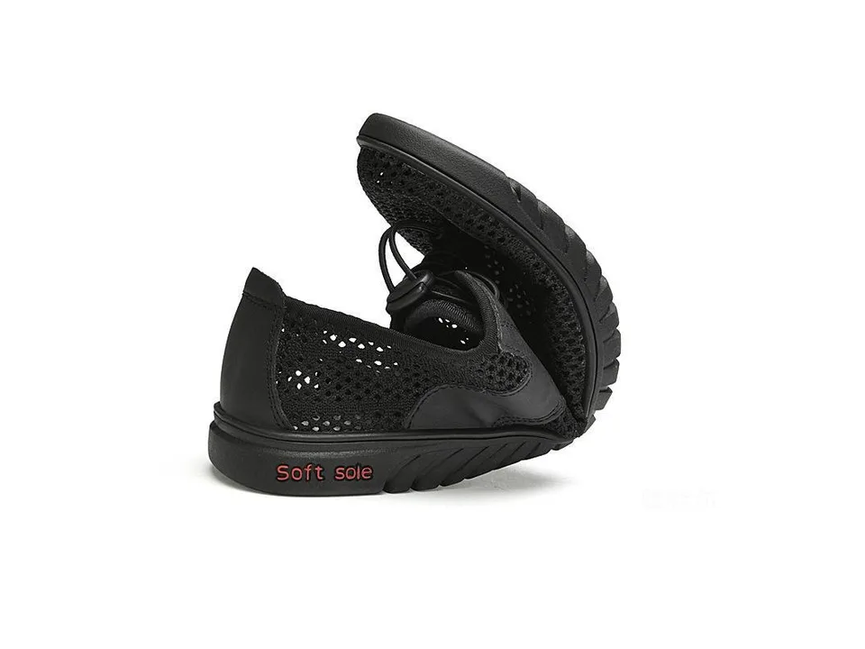 A black mesh sneaker being folded to show its flexible soft sole.