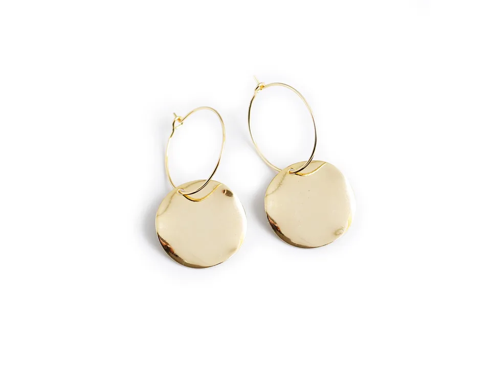 Two gold hoop earrings with wavy disc pendants on a white background.