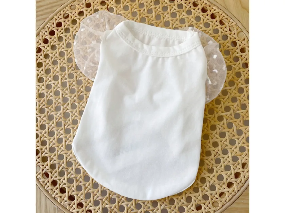 A white pet dress with mesh puff sleeves laid flat on a woven surface.