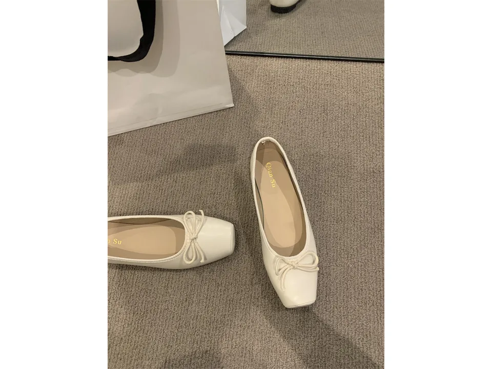 A pair of cream-colored square toe ballet flats with a bow detail.