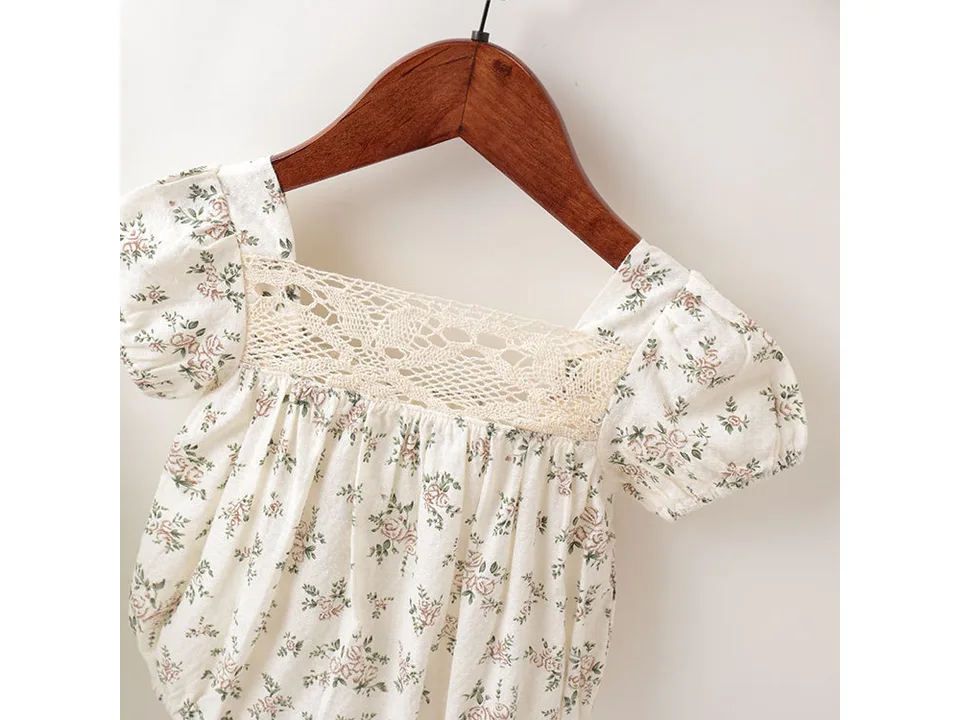 Close-up of the lace neckline and floral fabric of the baby romper.