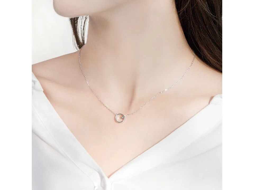 A woman wearing the silver circular pendant necklace.
