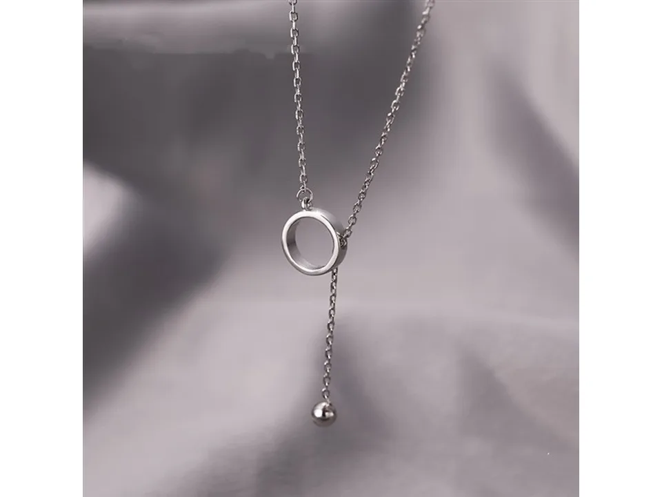 Silver lariat necklace with a circular pendant and a small bead drop.