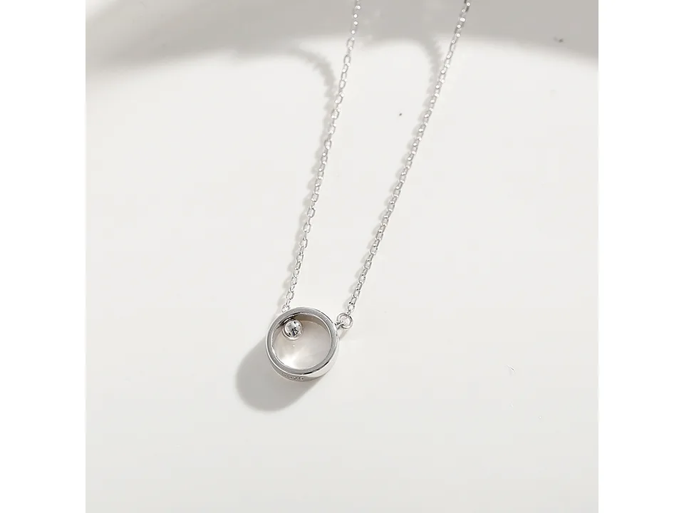 Close-up of the silver circular pendant with a small bead inside.