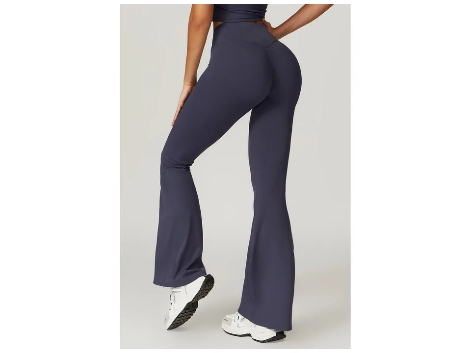 Rear view of dark blue high-waisted flare yoga pants on a model.