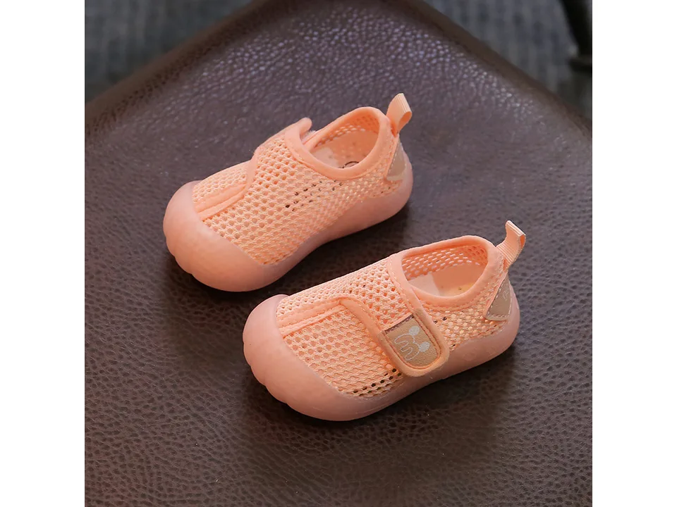 Pair of orange breathable mesh baby sneakers with velcro closure.