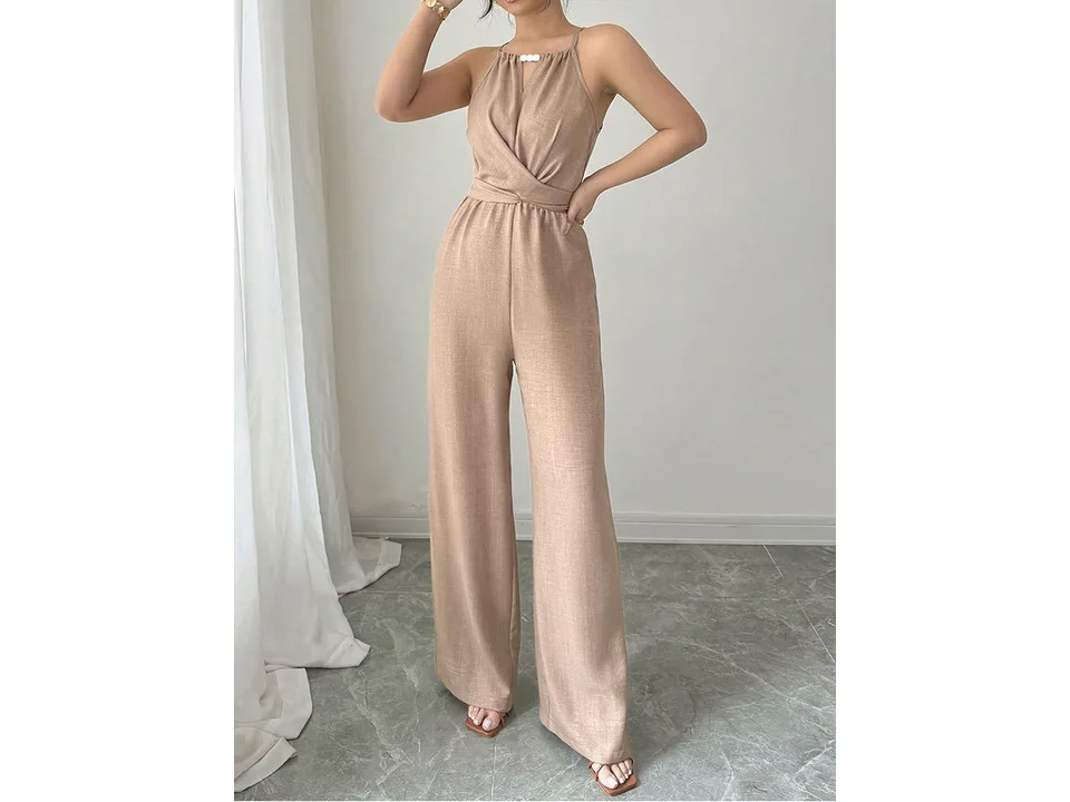 A model wearing a beige sleeveless high-waisted jumpsuit with a halter neck.