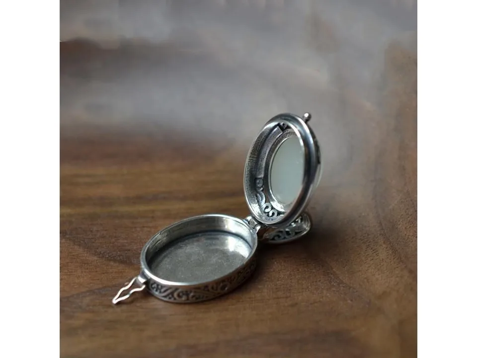 Open silver locket pendant with a jade inlay, showing the empty interior compartment.