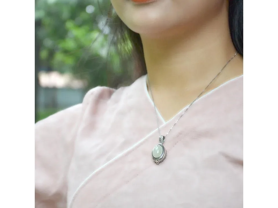 A person wearing the silver and jade locket necklace.