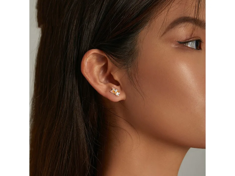 A close-up of a woman wearing a corgi stud earring in her ear.
