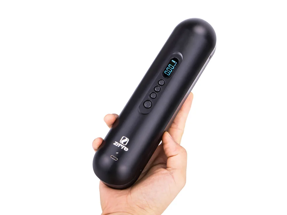 A hand holding the black portable electric air pump to show its compact size.