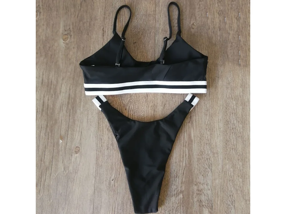 Black two-piece bikini with white striped trim on a wooden background.
