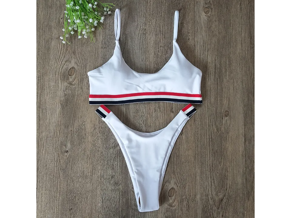 White two-piece bikini with red, white, and blue striped trim on a wooden background.