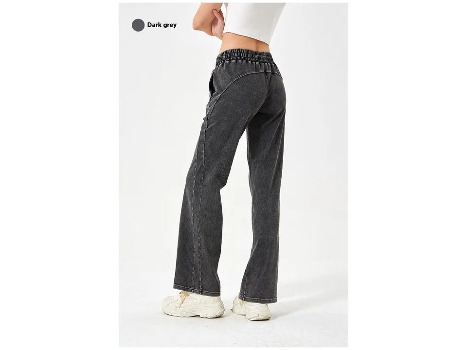 Back view of a woman wearing dark grey loose fit denim jeans.