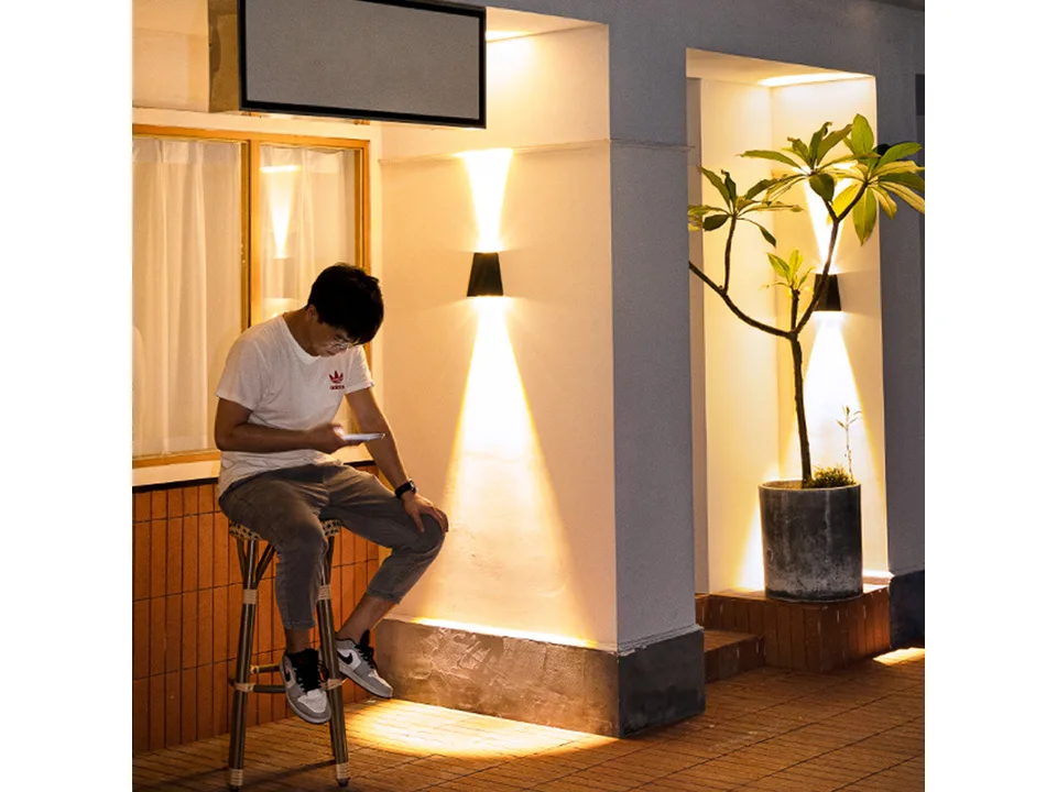 Solar wall lamp installed on an outdoor wall, illuminating the area at night.