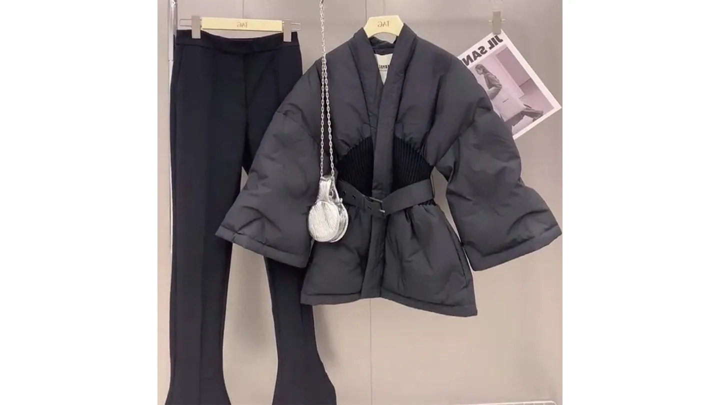 A black cotton-padded winter coat with a belt and ribbed waist, displayed with matching black trousers.