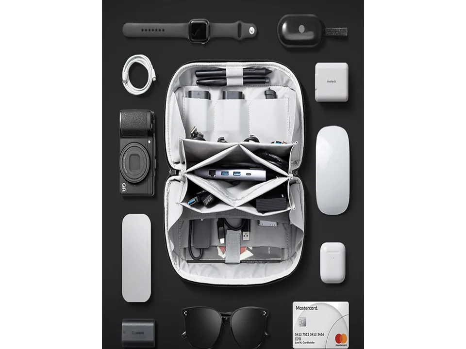 The open storage bag filled with various electronic accessories like cables, a mouse, and a camera.