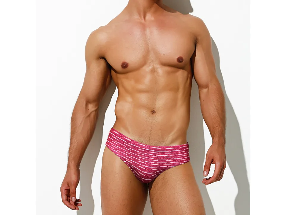 A man wearing red patterned swim briefs, front view.