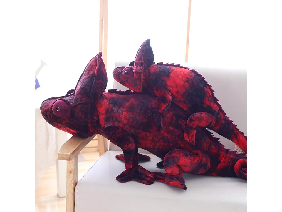 A red plush chameleon toy resting on a sofa.