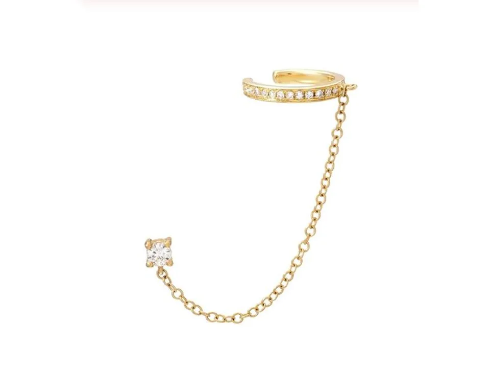 A gold ear cuff connected to a single crystal stud by a delicate chain.