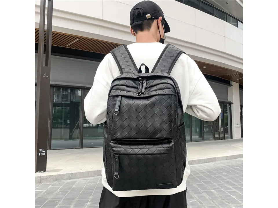 Person wearing the black woven backpack, back view.
