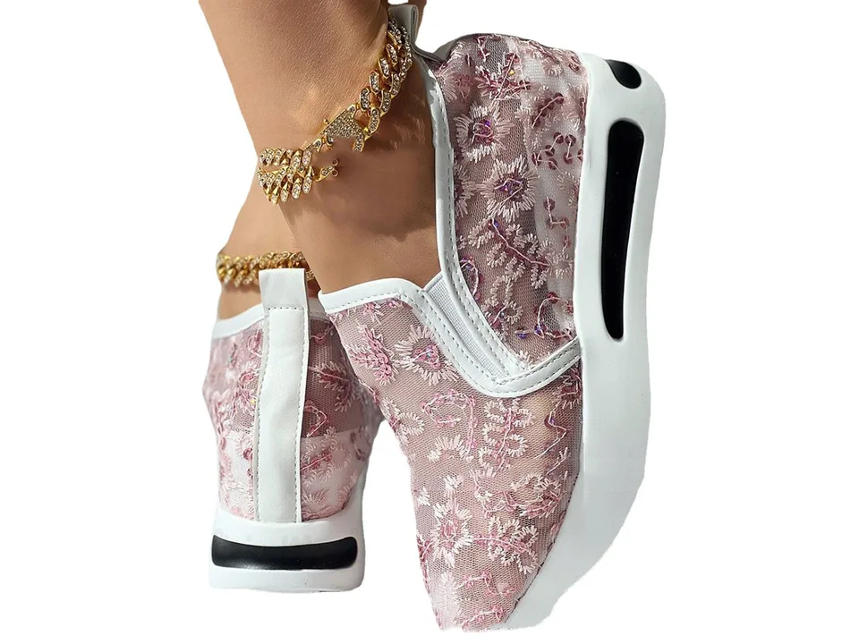 A close-up view of a pink floral mesh slip-on shoe with a white platform sole worn on a foot.