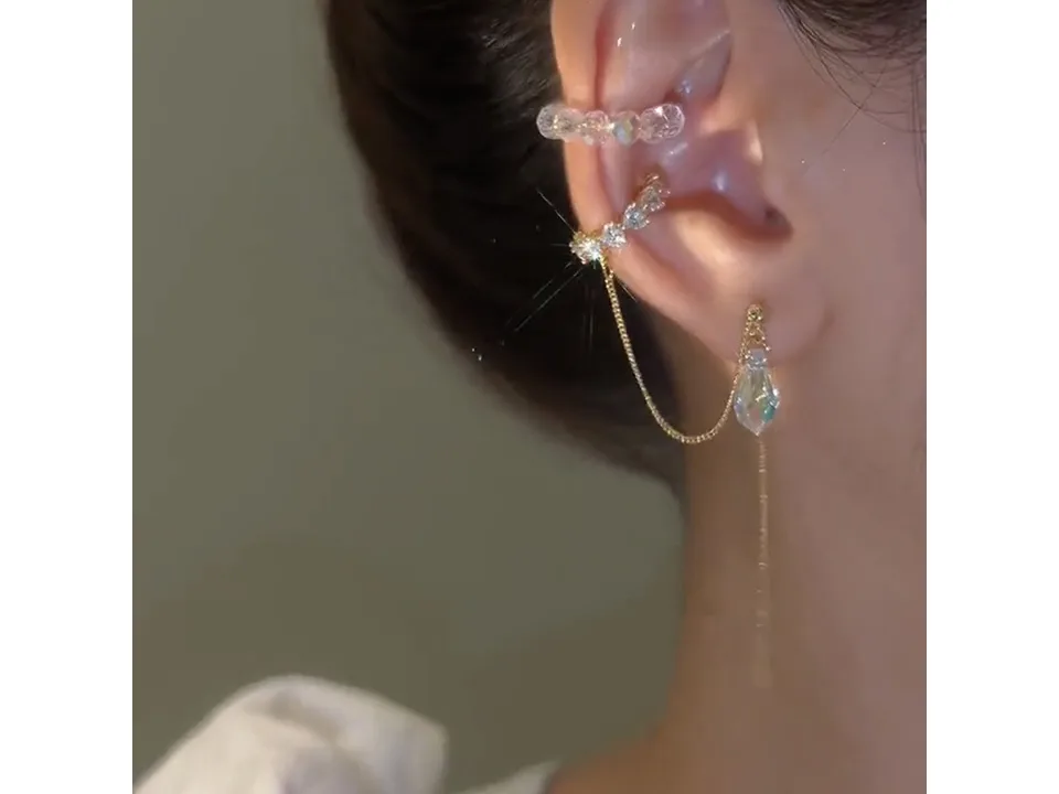 A person wearing both the crystal ear cuff and the chain-connected drop earring.
